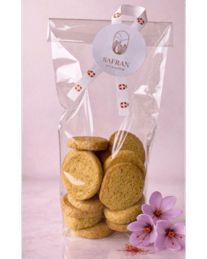 Vue sur un sachet de biscuits sablés au safran à côté de trois fleurs de safran et quelques stigmates rouges