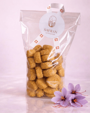 Vue sur un sachet de biscuits apéritifs au safran à côté de trois fleurs de safran et quelques stigmates rouges