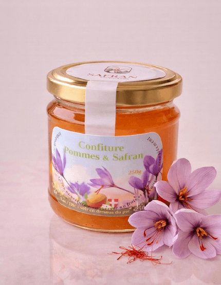 Vue sur un pot de confiture de pommes au safran à côté de trois fleurs de safran et quelques stigmates rouges