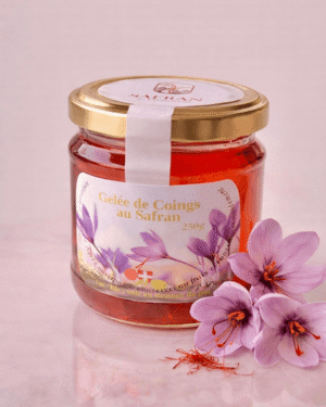 Vue sur un pot de gelée de coings au safran à côté de trois fleurs de safran et quelques stigmates rouges